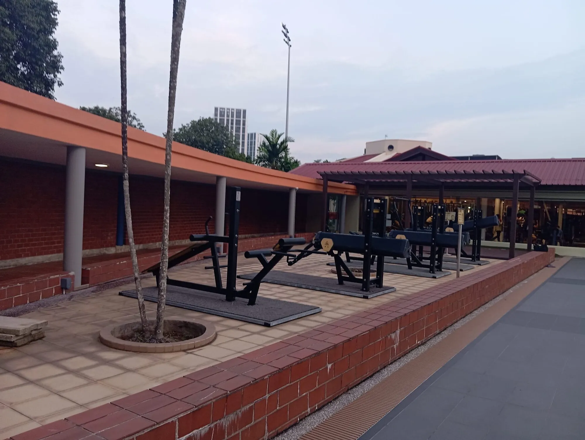 Outdoor strength-training machines under a shelter beside the pool deck