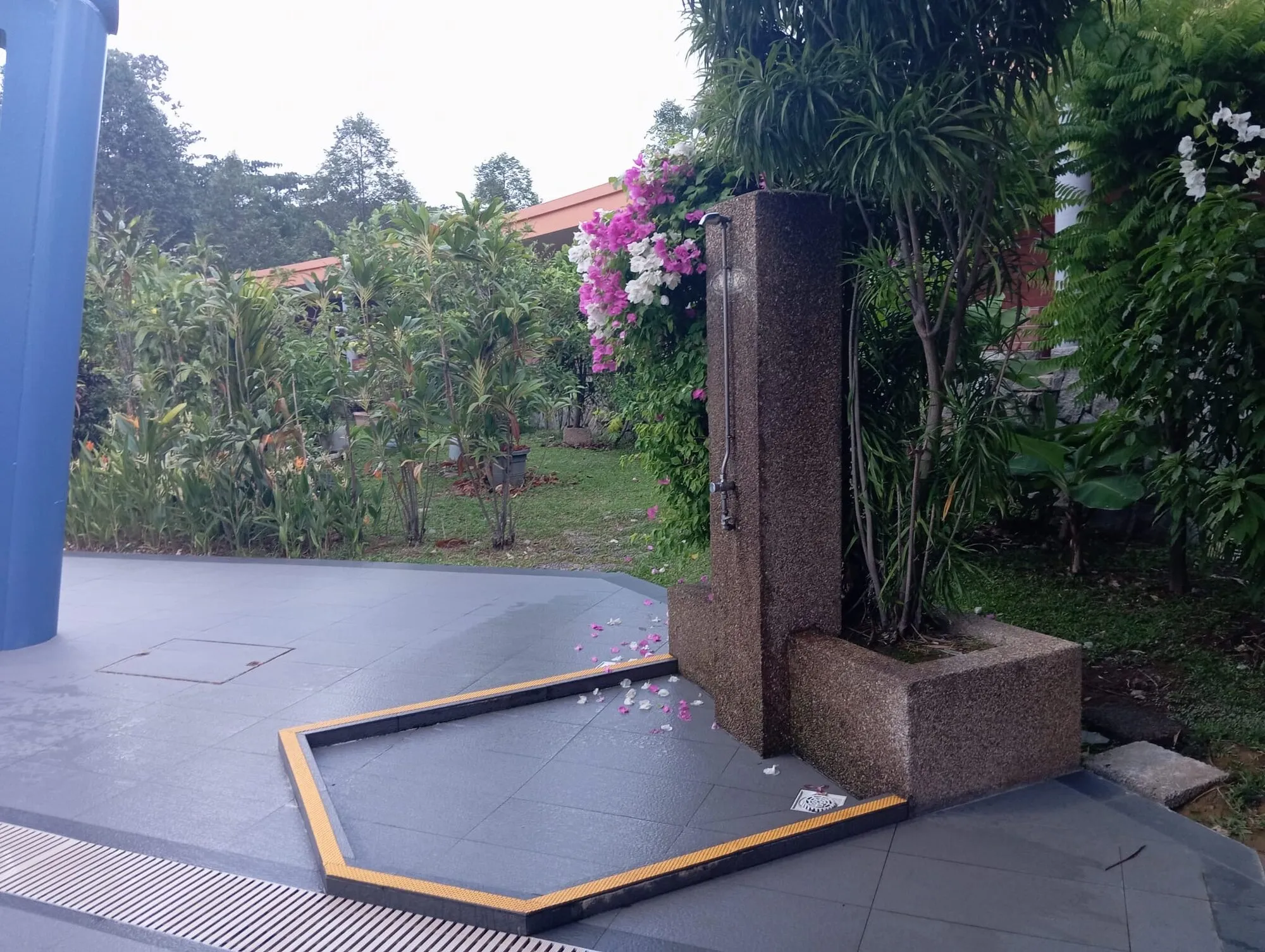 A granite rinse shower in a garden corner of the pool deck