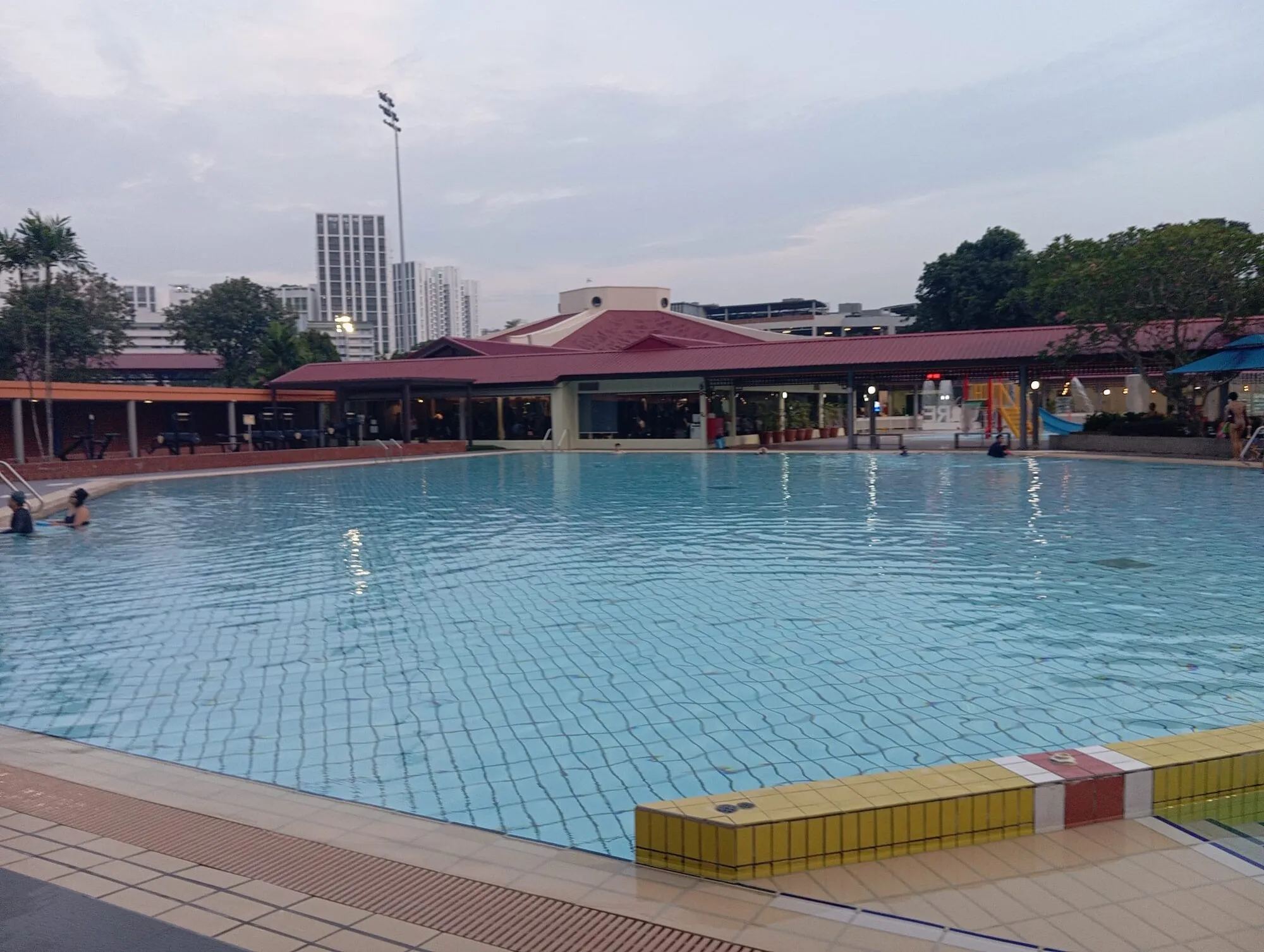 The large free-form teaching pool with a yellow and red tiled step ledge in the foreground